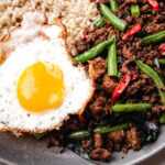 Thai basil chicken with rice and fried egg on a blue plate.