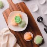 Green and orange mochi ice cream on a white place.