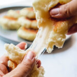 Potato pancake being pulled apart with cheesy center.