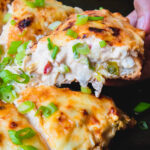 Pulling rangoon pizza on baking tray topped with green onions.