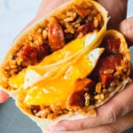 Holding halves of a longanisa burrito with egg inside.
