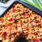 Square baking tray with sushi bake inside with a scoop missing.