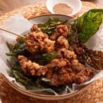 A white bowl of crispy Taiwanese popcorn chicken with basil.