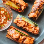 Baked salmon rolls with dipping sauce on a blue plate.