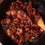 Wok of beijing beef with sesame seeds and wooden spatula.