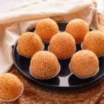 Blue plate of sesame balls on a woven beaded placemat.