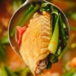 Close-up of ladle of chicken sinigang above the pot.