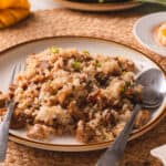White plate of adobo fried rice with a silver spoon and woven placemat.