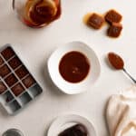 Tamarind paste as a concentrate, ice cubes, and in measuring cup on a white table.