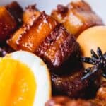White bowl of thit koh with pork belly, boiled egg, & star anise.