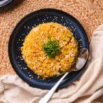 Golden fried rice on a blue plate topped with green onions & sesame seeds.