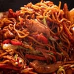 Chicken lo mein recipe in a wok with a wooden spoon.