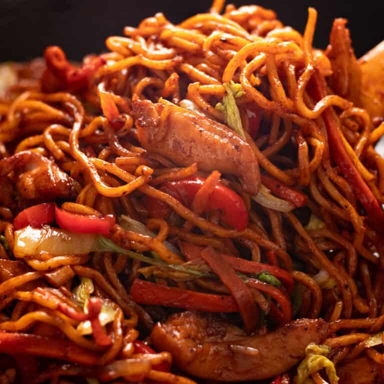 Chicken lo mein recipe in a wok with a wooden spoon.
