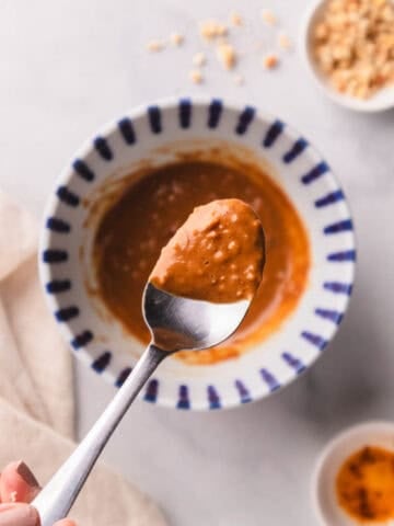 Peanut sauce mixed with crushed peanuts with a silver spoon.