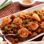 Shrimp fried rice on a white rectangle plate on a beaded placemat.