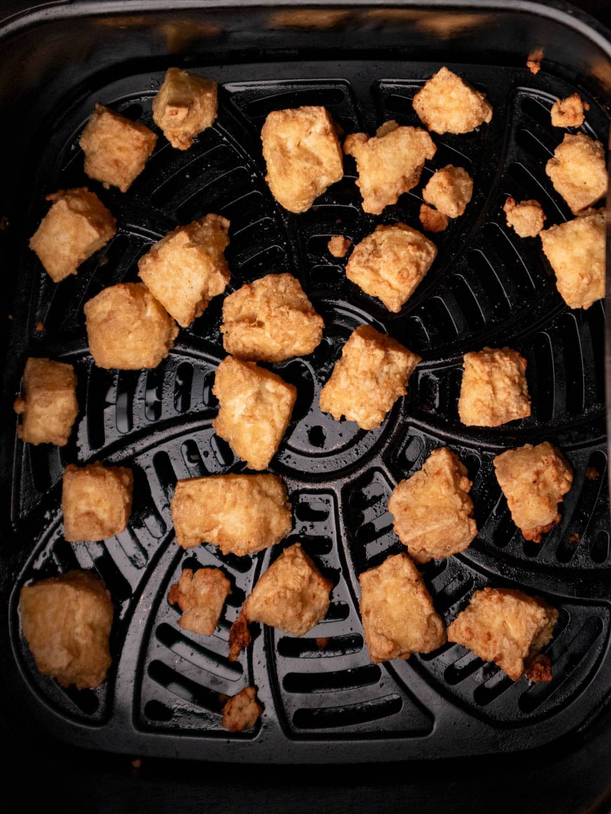 Crispy golden tofu cooked in an air fryer tray.