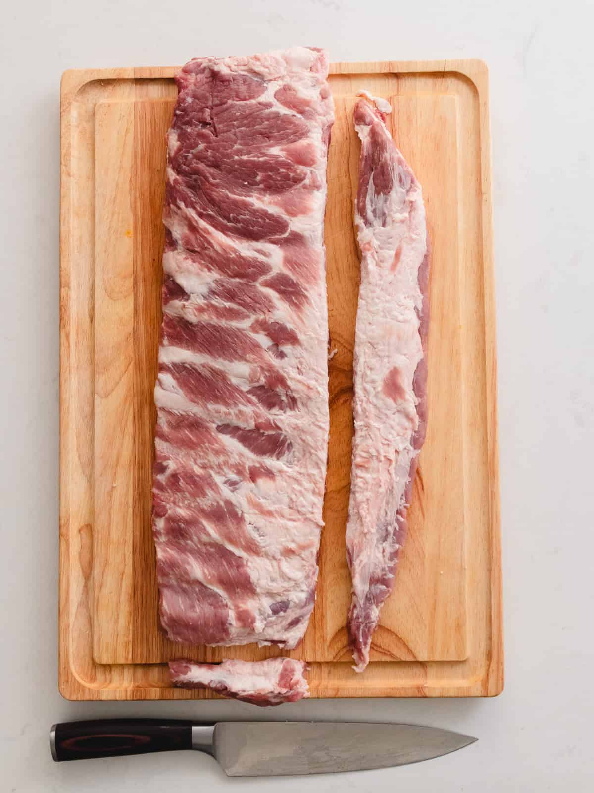 Cutting pork spare ribs to St. Louis Style cut on a wooden cutting board.