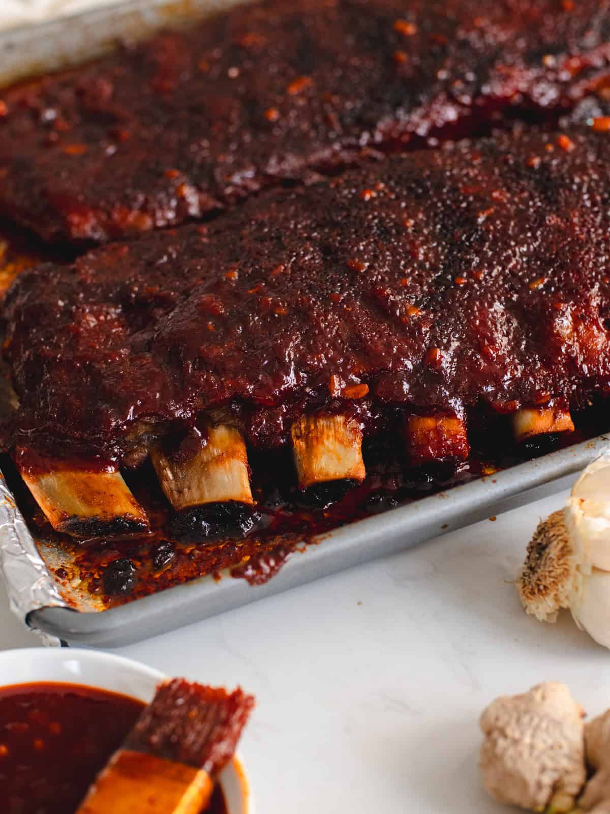 Korean bbq spare ribs on a baking sheet brushed with Korean bbq sauce.