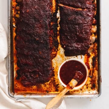 Korean bbq ribs on a baking sheet slathered in gochujang bbq sauce.