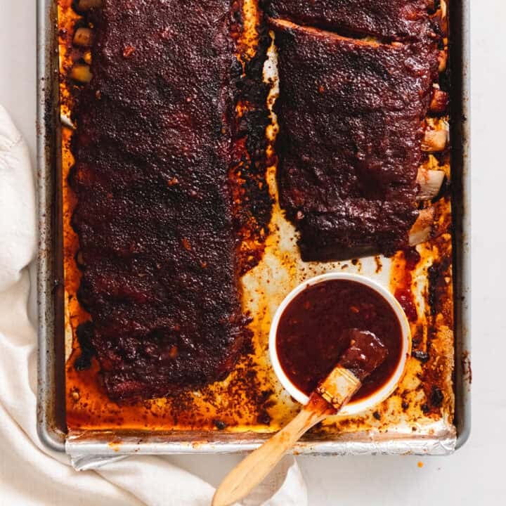 Korean bbq ribs on a baking sheet slathered in gochujang bbq sauce.