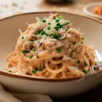 Miso pasta in a white and brown rimmed bowl with chives and parmesan.