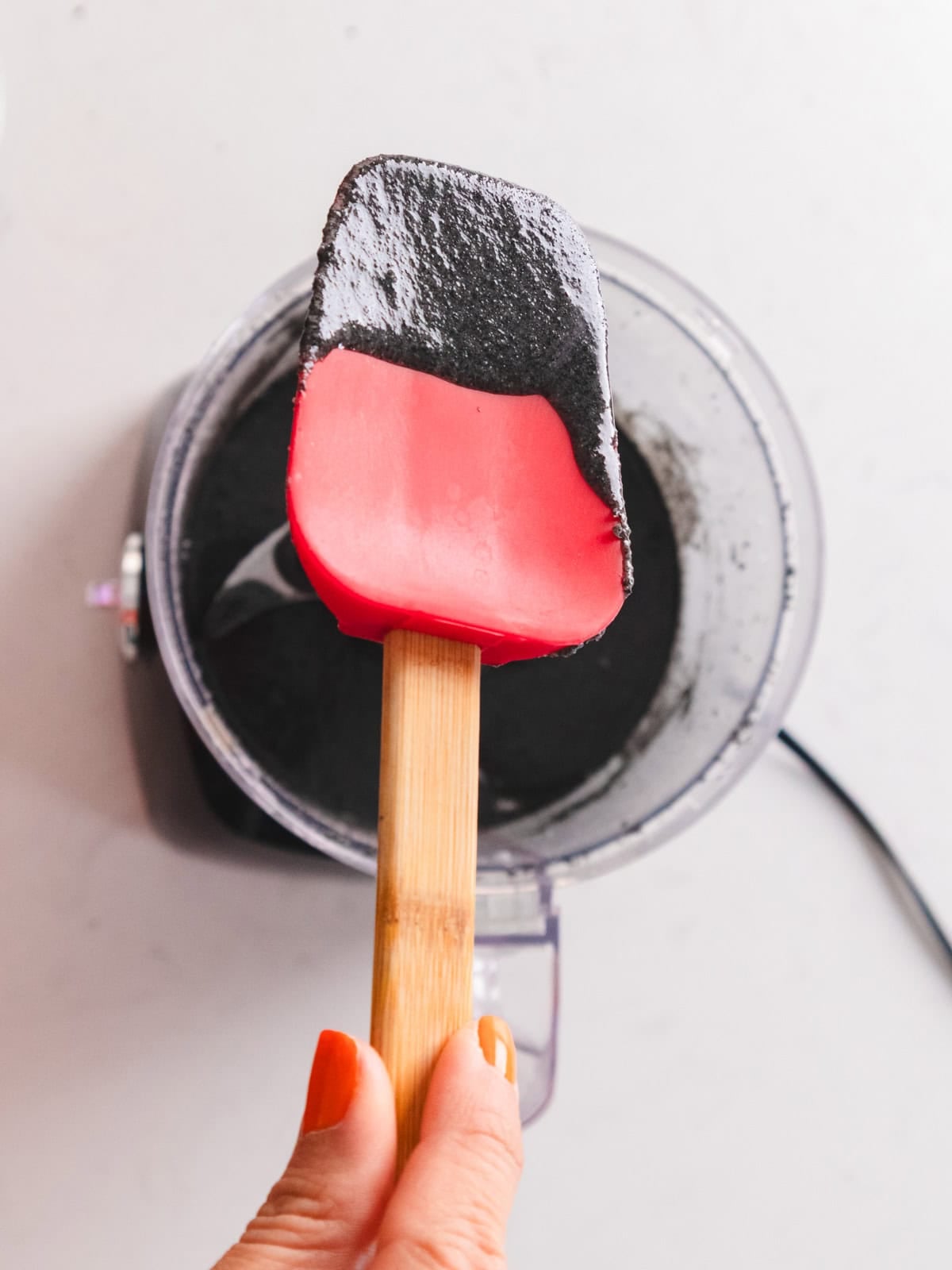 Tangyuan black sesame paste dripping off spatula into food processor.