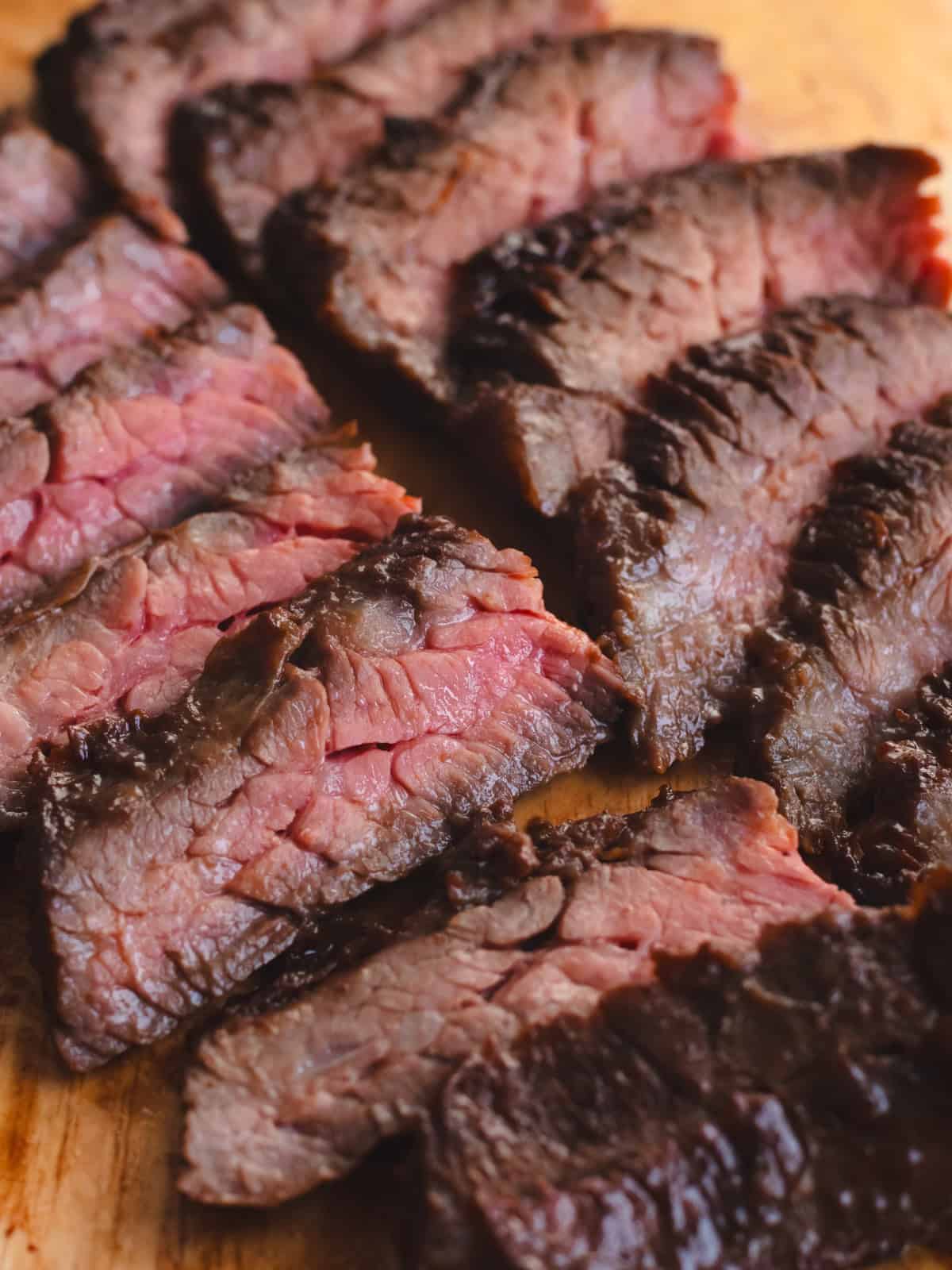 Cut marinated skirt steak against the grain on a wooden cutting board.