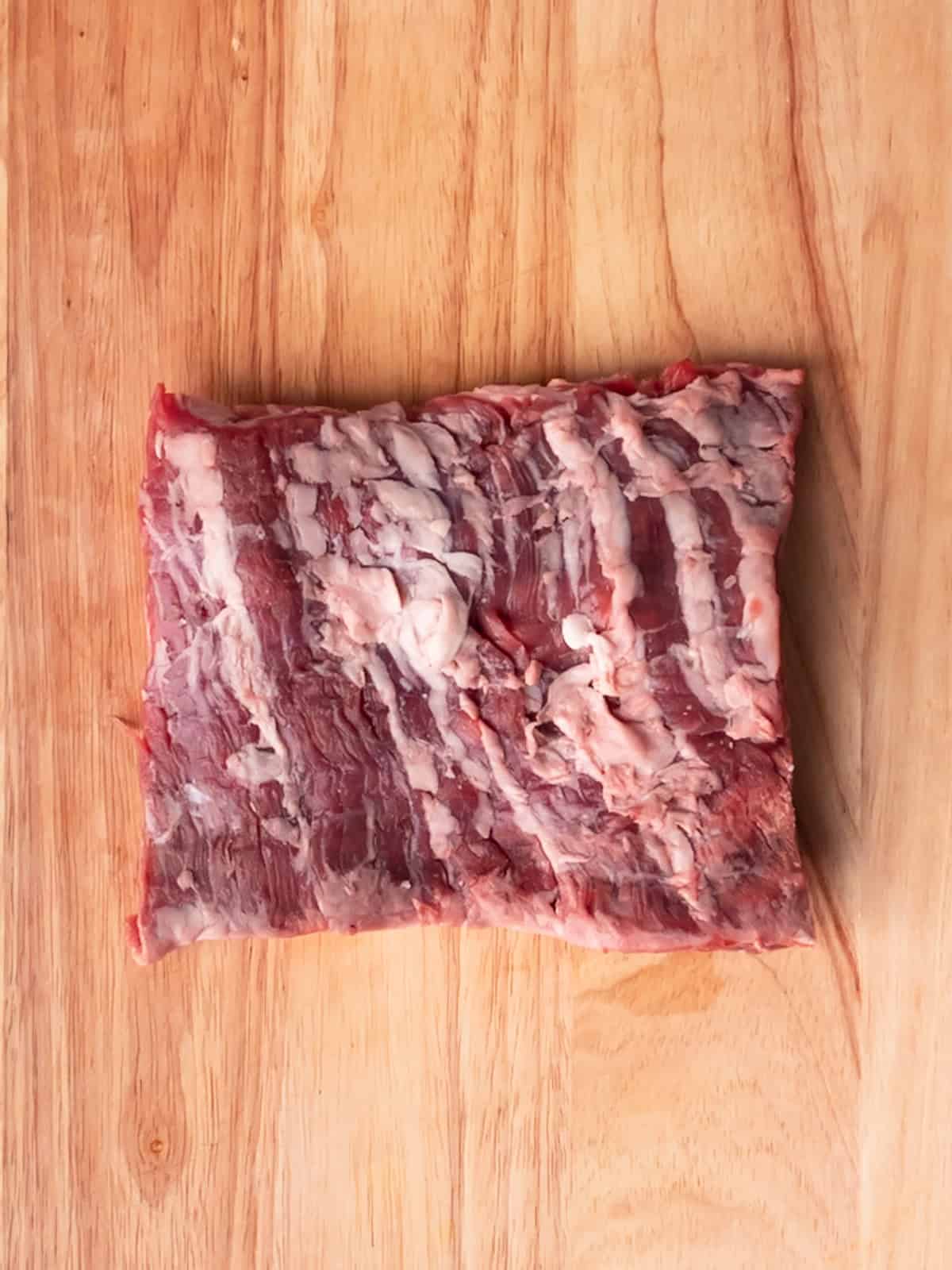 Raw skirt steak on a wood cutting board.