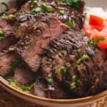 Asian marinated skirt steak on white rice and side of tomatoes.