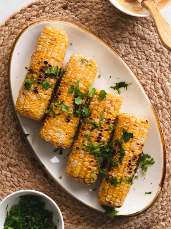 Skillet roasted miso corn on a white oval plate garnished with cilantro.