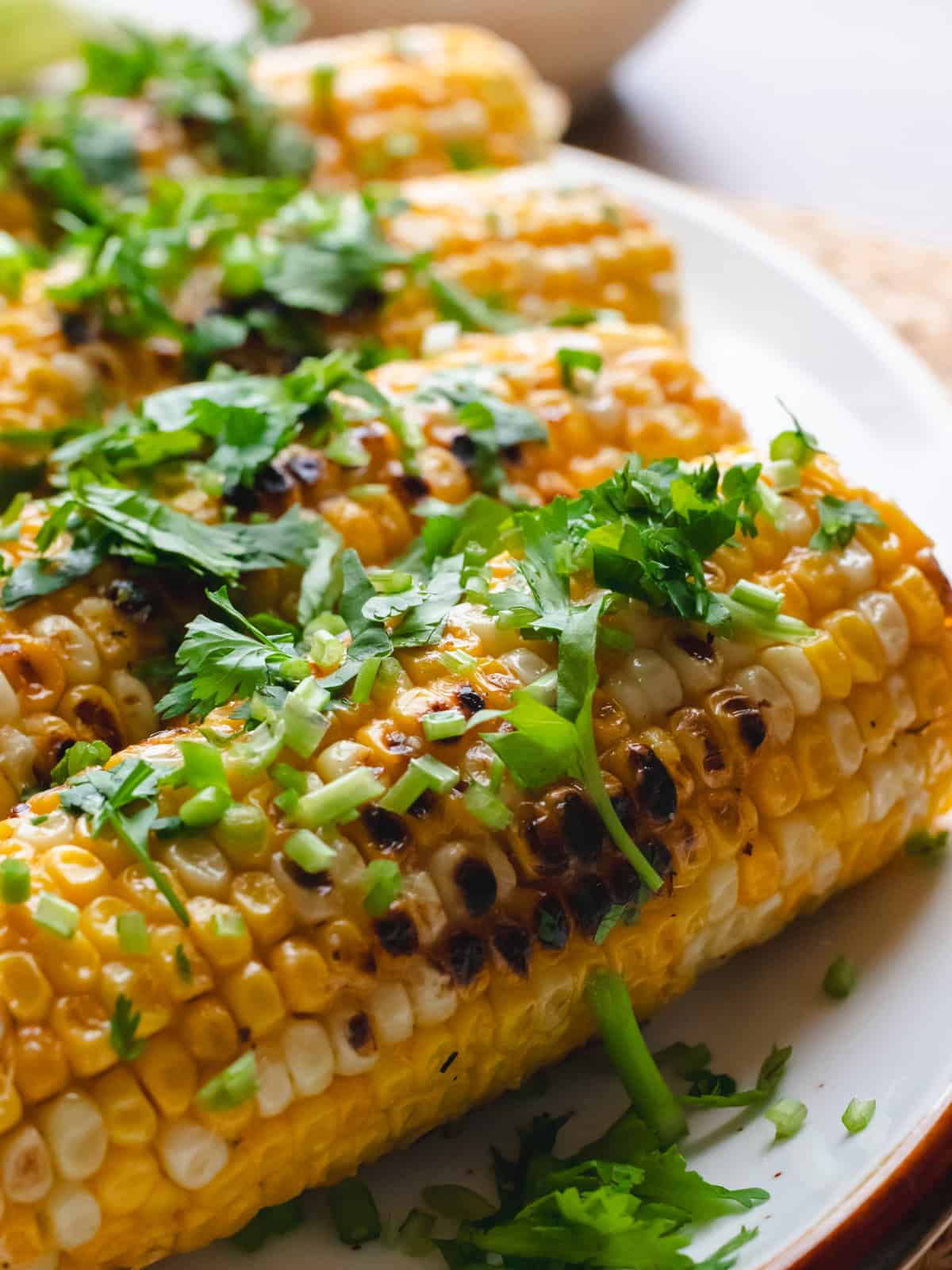 Miso butter corn garnished with cilantro on a white oval plate.