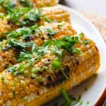 Miso butter corn garnished with cilantro on a white oval plate.