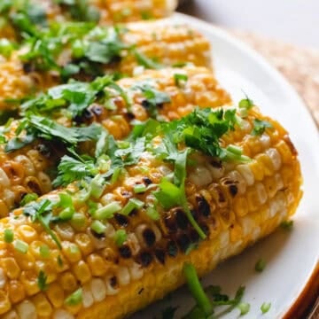 Miso butter corn garnished with cilantro on a white oval plate.