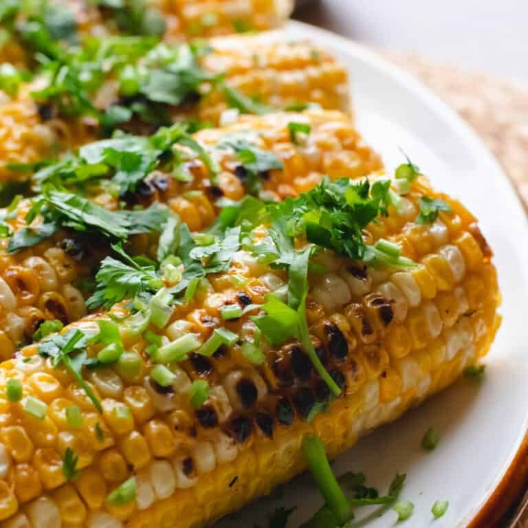 Miso butter corn garnished with cilantro on a white oval plate.
