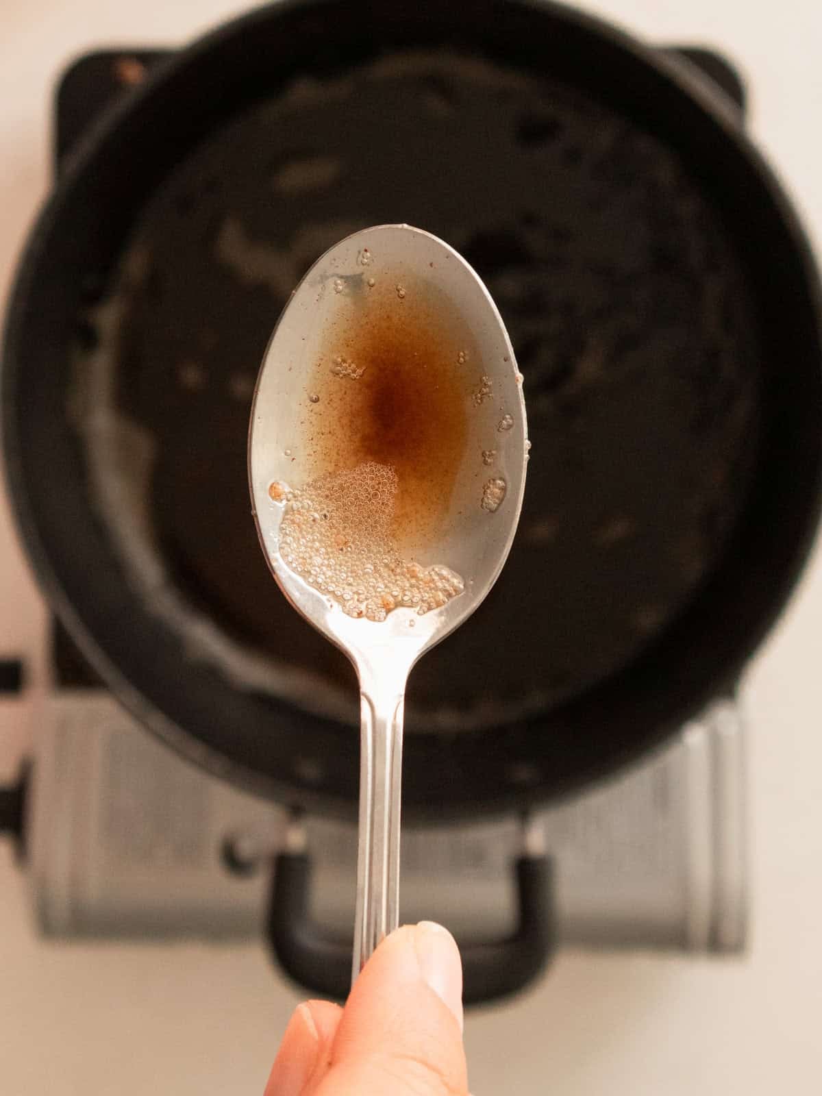Silver spoon of browned butter above pot.