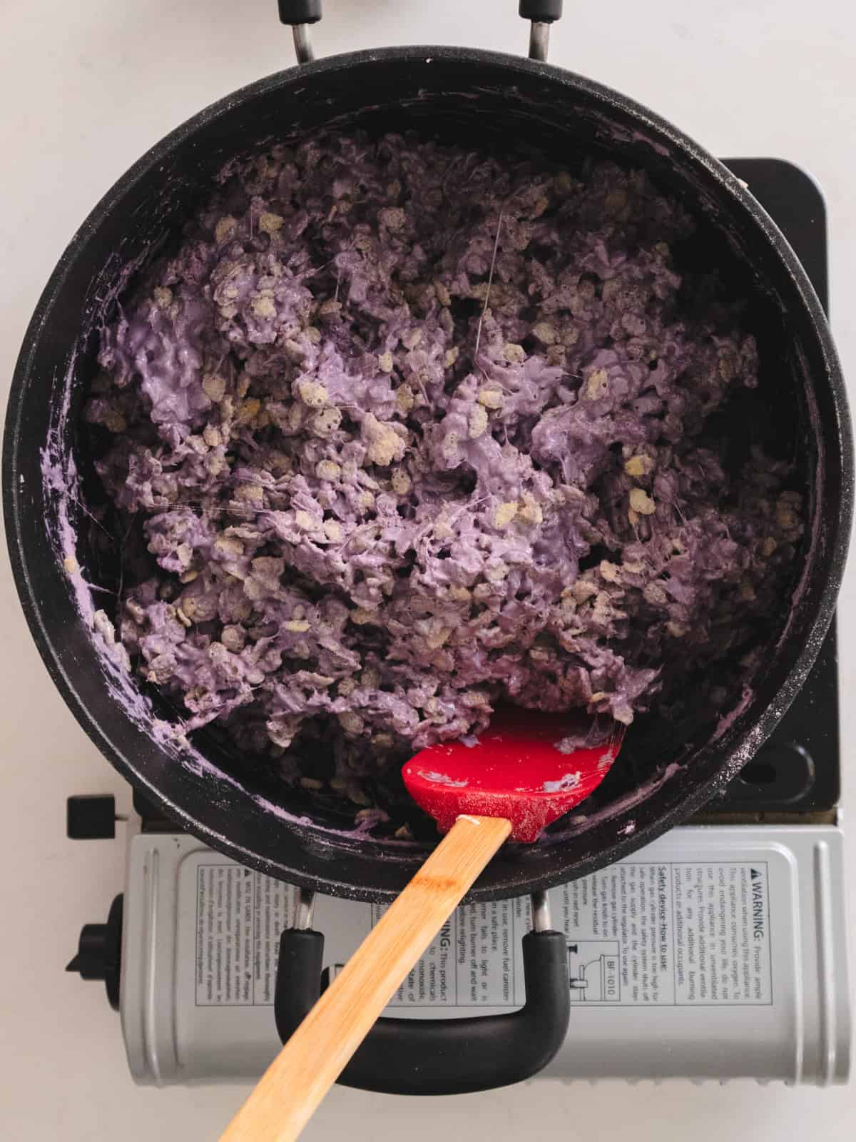 Taro rice krispies treats mixed in a large black pot.